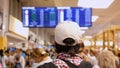 Backpacker checking flight information on digital schedule display inside arrival hall in international airport. Royalty Free Stock Photo