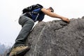 Backpacker climbing rock on mountain top cliff edge Royalty Free Stock Photo