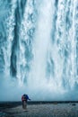 Backpacker couple standing at powerful waterfall in summer