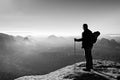 Backpacker with eyeglasses and poles in hand. Sunny day in rocky mountains. Hiker with big backpack on rocky view point above mist Royalty Free Stock Photo