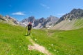 Backpacker hiking on footpath and looking at expansive view from the top. Summer adventures and exploration on the Italian French Royalty Free Stock Photo