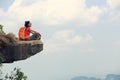 Successful young woman backpacker sit on the cliff edge on mountain top Royalty Free Stock Photo