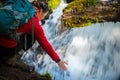 Backpacker holding hand under running water of clearwater falls