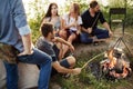 Backpacker is holding a sausage above the campfire