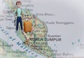 Backpacker with luggage stand on Malaysia map