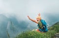 Backpacker man has a rest break enjoying cloudy valley bottom walking by the foggy cloudy weather mountain range . He is rising a Royalty Free Stock Photo