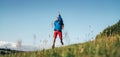 Backpacker traveler emotionally jumping over green grass mountain meadow with backpack with wide opened arms and legs. Human`s