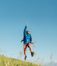 Backpacker traveler emotionally jumping over green grass mountain meadow with backpack with wide opened arms and legs. Human`s