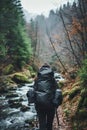 Backpacker walking along a river trail in a forest, with mossy rocks and autumn leaves. Royalty Free Stock Photo