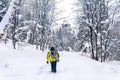 Backpacker walks along a path in a winter forest, following a quadcopter