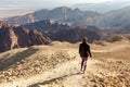 Backpacker woman descending hiking mountain ridge desert landscape. Royalty Free Stock Photo