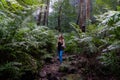 backpacker woman with poles stands along a path through the jungle