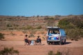 Backpackers with their white campervan sitting in camping chair