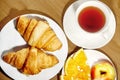 Backround continental breakfast with gold french croissants, fruits and cup of tea on wooden table. Great choice on morning. Tasty Royalty Free Stock Photo