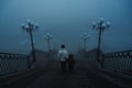 backs of a woman with a child boy going down the stairs on a foggy bridge in the city on an autumn morning in fog mist Royalty Free Stock Photo