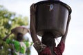 Backshot Of A Young African Girl Carrying Heavy Water Bucket Back Home From the Village Borehole