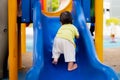 Backside of Asian baby boy climbs the children's slide on playground. Child playing happily in summer or spring times. Royalty Free Stock Photo