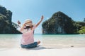 Backside of asian child girl wearing hat sitting on the beach and enjoying with beautiful nature