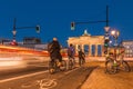 Brandenburg Gate at night with cyclists at the traffic lights