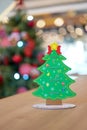 Backside Christmas tree paper craft decoration on the wood table with blur big Christmas tree behide