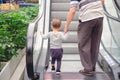 Backside of Cute little Asian 18 months / 1 year old toddler baby boy child and dad holding hands on moving escalator