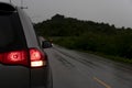 Backside of family gray car stop on asphalt road with rain.