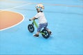 Backside of little Asian toddler boy child wearing safety helmet learning to ride his first balance bike, kid playing & cycling at Royalty Free Stock Photo