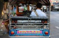 Backside of man driver sitting in his three-wheeled motorized vehicle used as a taxi Tuk Tuk. To wait for passengers beside the