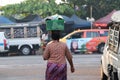 Backside of Myanmese woman put the plastic basket on her head, from going to market