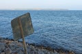 Backside of the old information plate on the pebble beach. Little waves on the water`s surface in the background. Autumn sunny day