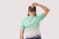 Backside portrait of middle aged bald man with beard in light green t-shirt standing, scratching his head or thinking about Royalty Free Stock Photo