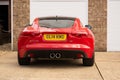 Backside of a red F-type Jaguar luxury car parked in front of a building