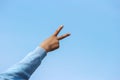 backside of a victory sign from a young girl hand with blue sky as background.