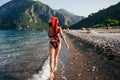 Backside view of bikini woman in Santa hat walking carefree along the beach