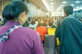 Backside view of spectators standing in a gathering in the back of auditorium full of people.