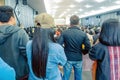 Backside view of spectators standing in a gathering in the back of auditorium full of people.