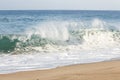 Backspray cresting wave with backwash foam breaking on a sandy shoreline Royalty Free Stock Photo