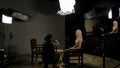 Backstage shot of woman guest preparing for recording interview in stylish podcast studio, sound engineer fixing setting