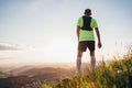 Backview of Active mountain trail runner dressed bright t-shirt with backpack enjoying the sunset while he sky running by
