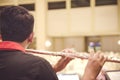 Backview, boy playing flute with his orchestra on the stage