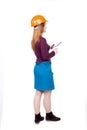 Backview of business woman in construction helmet stands and enjoys tablet or using a mobile phone. Royalty Free Stock Photo