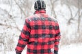 Backview of man in red buffalo check jacket in the snow