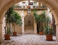 Backyard with arch, plants in pots, stairs and lantern. Patio decoration. Ancient courtyard background. Medieval architecture. Royalty Free Stock Photo