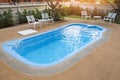 Backyard area with swimming pool blue water and tables chairs and trees fenced background , swimming pool garden Royalty Free Stock Photo