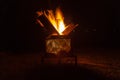 Backyard campfire in brazier against night sky with lights in the background - , family fun in autumn or spring holidays. Royalty Free Stock Photo