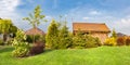 Backyard of a family house. Landscaped garden with green mown grass, wood shelter.