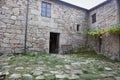 Backyard of old house in village. Stone medieval building with open entrance and windows. Royalty Free Stock Photo