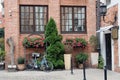 The backyard of an old red brick house in the Polish city of Gdansk with two large windows, a back door, flower beds