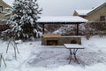 Backyard Patio.Landscape with barbeque area, snowbanks of white snow, pine trees in country garden.