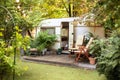 Backyard with RV house with garden furniture. Two deckchairs near outside caravan trailer. Royalty Free Stock Photo